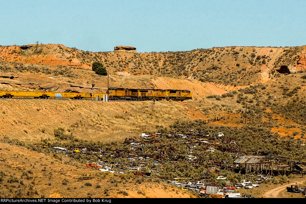 Eastbound manifest freight passing the automobile junkyard